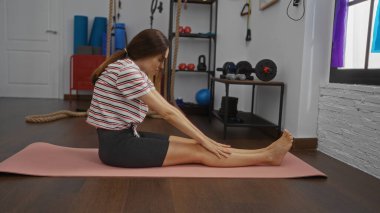 Spor salonunda paspasın üzerinde uzanan genç bir kadın.