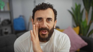 Sakallı adam rahat oturma odasında fısıldıyor.