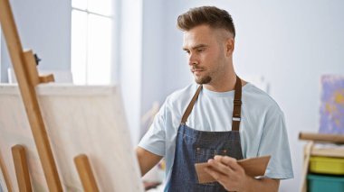 Parlak bir sanat stüdyosunda resim yapan yakışıklı İspanyol bir adam yaratıcılık ve konsantrasyonu resmediyor..