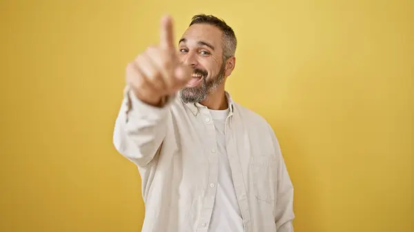 stock image Cheerful mature hispanic man with grey beard pointing smiling against yellow background