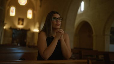 Genç ve güzel bir İspanyol kadın Hıristiyan sembolleri ve vitray pencerelerle çevrili İtalya 'da bir kilisede dua ediyor..