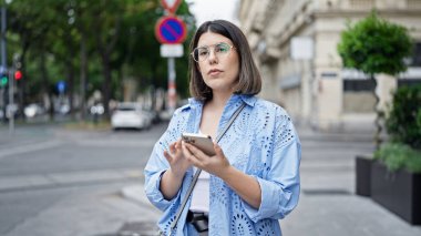 Genç ve güzel İspanyol kadın Viyana sokaklarında akıllı telefon kullanıyor.