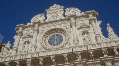 Karmaşık heykeller ve tarihi şehir Puglia, İtalya 'da geniş yuvarlak bir pencere ile süslü mimari, derin mavi bir gökyüzü altında yakalandı..