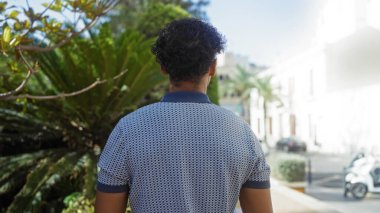 Gündüz vakti yemyeşil bitkiler ve şehir binalarıyla şehir parkında dikilen adam