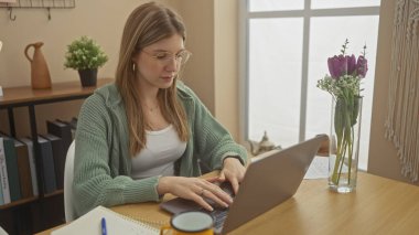 Odaklanmış bir kadın rahat bir ofis ortamında dizüstü bilgisayarla çalışır..