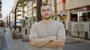 Sakallı çekici genç adam hareketli bir şehir caddesinde kendine güvenerek duruyor, şehir yaşam tarzını somutlaştırıyor..