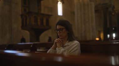 Genç bir İspanyol kadın, İtalya 'da loş bir Hıristiyan kilisesinde tek başına dua ediyor, dingin ve güzel bir inanç ve bağlılık anını yansıtıyor..