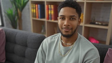 Yakışıklı bir Afro-Amerikalı adam modern ev dekorlarıyla çevrili bir şekilde evde takılıyor..