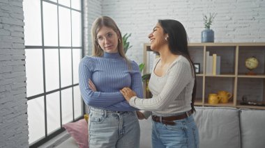 Two women standing together in a cozy living room, exuding warmth and friendship. clipart