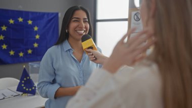 İki kadın, Avrupa bayrağıyla kapalı alanda röportaj yapıyor ve siyaset veya gazetecilik önerisinde bulunuyor