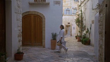 Genç İspanyol bir kadın polignano 'nun büyüleyici sokaklarında yürüyor. Güzel bir günde güzel Avrupa manzarasını keşfeden puglia, İtalya' da bir kısrak..