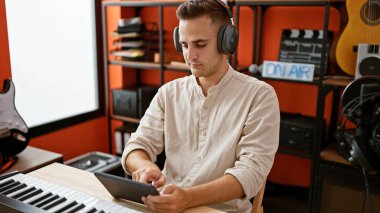 Müzik stüdyosunda tablet kullanan kulaklıklı İspanyol bir genç.