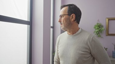 Latin kökenli olgun erkek profili. İçerde, gözlük takıyor. Düşünüyor.