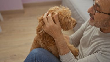 Olgun bir adam kanişini sıcak bir oturma odasında sevgiyle okşar. Huzurlu bir aile anını somutlaştırır..