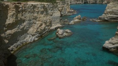 Torre Dell 'orso, Salento, Puglia, İtalya' da berrak mavi deniz sularına sahip güzel sahil kayalıkları doğal kaya oluşumları ve sakin manzaralar sergiliyor..