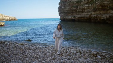 Polignano 'da güzel bir sahilde genç bir İspanyol kadın bir kısrak, puglia, İtalya, sakin Avrupa kıyı manzarasının tadını çıkarıyor..