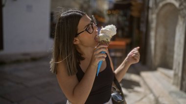 Genç bir İspanyol kadın, Puglia, İtalya 'daki yaşlı bir kasabanın büyüleyici sokaklarında dondurma yiyor. Avrupa' nın yaz atmosferini kucaklıyor..