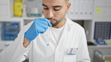 Laboratuvarın içinde laboratuvar önlüğü ve eldivenleriyle kimyasalın kokusunu alan bir adam araştırma çalışmalarına konsantre oluyor..