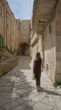Genç bir İspanyol kadın güneşli bir günde yaşlı güzel bir kasaba olan Mata, Basilicata, İtalya 'da yürüyor..
