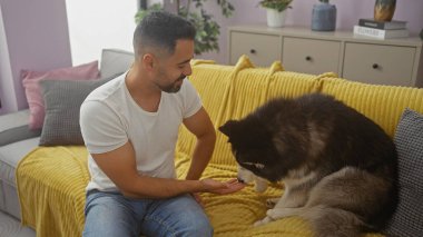 İspanyol adam rahat oturma odasında köpekle bağ kuruyor.