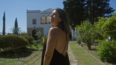Genç, güzel bir İspanyol kadın güneşli bir günde, yemyeşil ve tarihi mimariyle çevrili Puglia, İtalya 'da bir villada gülümsüyor..