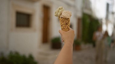 Locorotondo, puglia, İtalya 'nın eski sokaklarında dondurma külahını tutan genç bir kadın..
