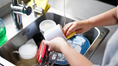 Genç ve güzel İspanyol kadın mutfakta tabak yıkıyor.