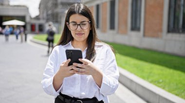 Madrid sokaklarında akıllı telefon kullanarak gülümseyen güzel İspanyol kadın.