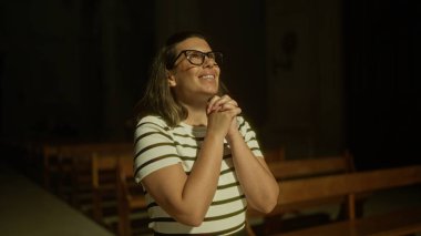 İtalya 'da bir kilisede, dramatik bir aydınlatma altında dua eden genç İspanyol kadın ellerini birbirine kenetleyerek inancını ifade ediyor..