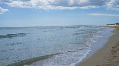 Pescoluse, salento, puglia, italyan vitrinleri sakin dalgalar, altın kum ve parçalı bulutlu gökyüzünün altında geniş bir ufuk..