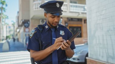 Afro-Amerikan polisi şehir caddesindeki tablete not alıyor..