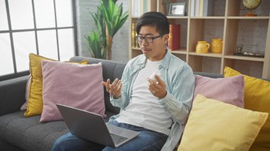 Asyalı bir adam, rahat bir oturma odasında sanal muayene sırasında ilaçları inceliyor..