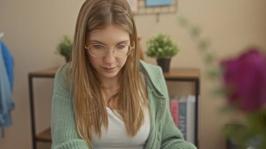 Ev dekoru, bitkiler ve kitaplarla çevrili evde kitap okuyan odaklanmış genç bir kadın..