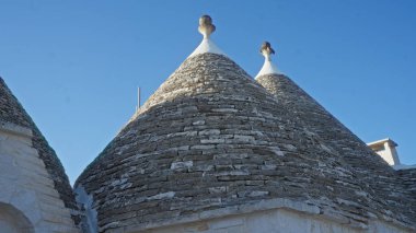 Avrupa 'nın pitoresk bir kasabasında alberobello, puglia, italyan, tarihi taş mimarisi açık mavi gökyüzü altında konik çatıları olan geleneksel trulli evler.