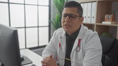 Laboratuvar önlüklü İspanyol doktor modern klinikteki bilgisayardaki verileri inceledi..