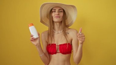 Mutlu ve gülümseyen bir kadın elinde güneş kremi ile izole edilmiş sarı arka planda onaylı bir tabela tutuyor.