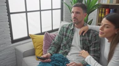 Sevgi dolu bir çift, rahat oturma odalarındaki kanepede sarılır ve birlikte sessiz bir anı paylaşır..