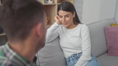 Hoş bir oturma odasında gülümseyen bir kadın ve bulanık bir adam, çifti, aşkı ve birlikteliği tasvir ediyorlar..