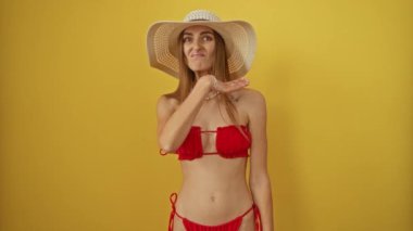 Bikinili bir kadın, saldırgan bir şekilde boğazını kesiyor. Kafkasyalı, tehditkar bir tavırla sarı arka planda, şiddet ve bıçak işareti ile izole edilmiş bir şekilde duruyor.