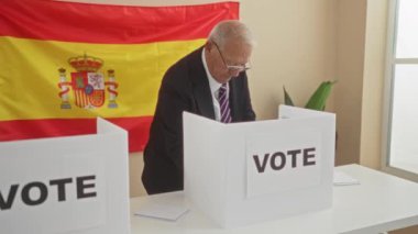 Arka planda İspanyol bayrağı olan kapalı bir seçim okulunda oy veren yaşlı bir adam İspanya 'daki demokratik süreci gösteriyor..