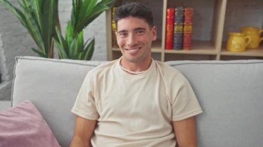 Kanepede oturan genç İspanyol adam yüzünde mutlu ve havalı bir gülümsemeyle. Şanslı insan. evde.