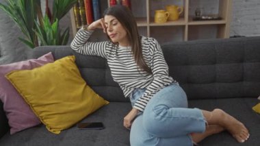 İspanyol kadın evde telefonuyla kanepede oturuyor, üzgün ve endişeli..