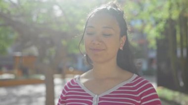 Sakin İspanyol kadın güneşli bir parkın keyfini çıkarıyor gözleri kapalı ve soluk bir gülümseme.