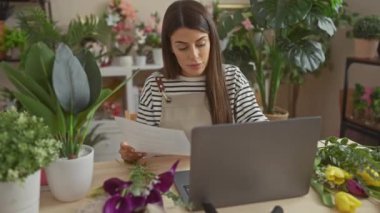 Etrafı bitkilerle ve dizüstülerle çevrili evde kitap okuyan İspanyol kadın, sakin bir ofis ortamını canlandırıyor..