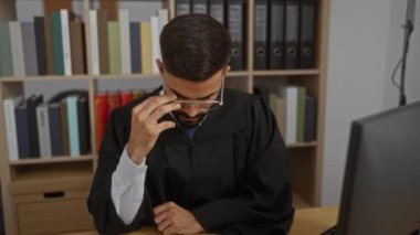 Genç İspanyol bir adam gözlüğünü çıkarıyor ve ofisteki çalışma odasında bilgisayarın önünde otururken düşünceli görünüyor.