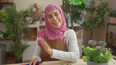 Evdeki defterde bitkilerle çevrili önlüklü, tesettürlü gülümseyen kadın.