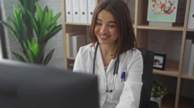 Genç bir İspanyol kadın doktor kliniğinde kutlama yapıyor, modern kapalı bir tıbbi iş yerinde neşe sergiliyor..