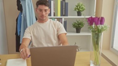 Evde dizüstü bilgisayar, defter ve iyi düzenlenmiş oturma odasında dinlenen yakışıklı İspanyol bir adam..