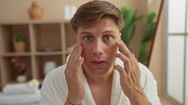 Kaplıca odasında yüzüne krem süren yakışıklı bir genç, sağlığını ve güzelliğini vurguluyor.