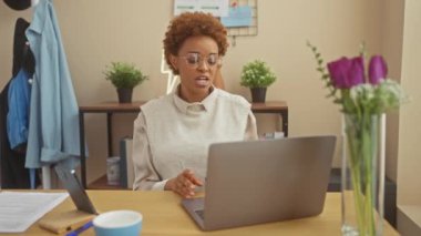 Çekici bir siyahi kadın, modern bir yaşam tarzı sergileyen, iyi aydınlatılmış bir ofis ortamında çevrimiçi bir sohbete girişiyor..